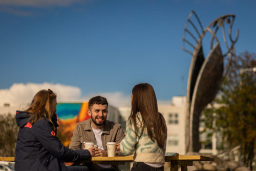 IT Sligo students having a chat in front of a mural on campus